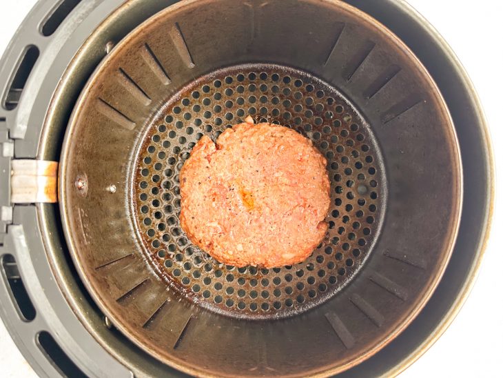 Hambúrgueres dentro da air fryer sendo assados a 200 °C.