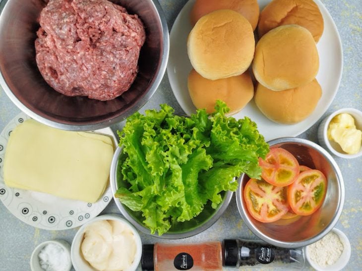 Ingredientes para a receita de hambúrguer simples separados em uma superfície.