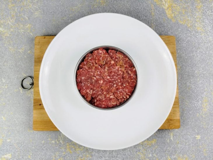 Carne colocada em um aro para modelar.