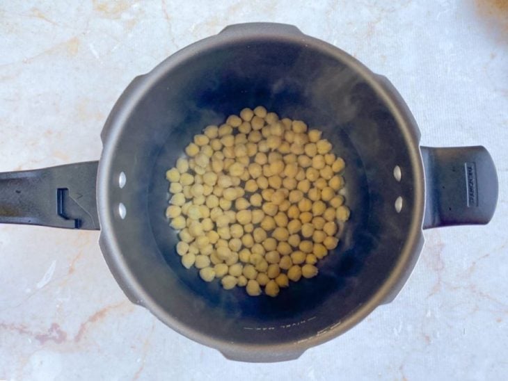 Grãos de bico em uma panela de pressão com água.