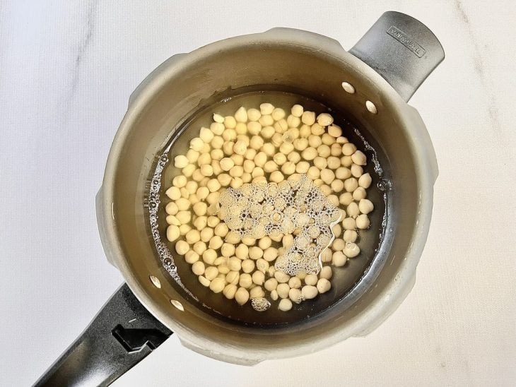 Grãos-de-bico numa panela de pressão com água.