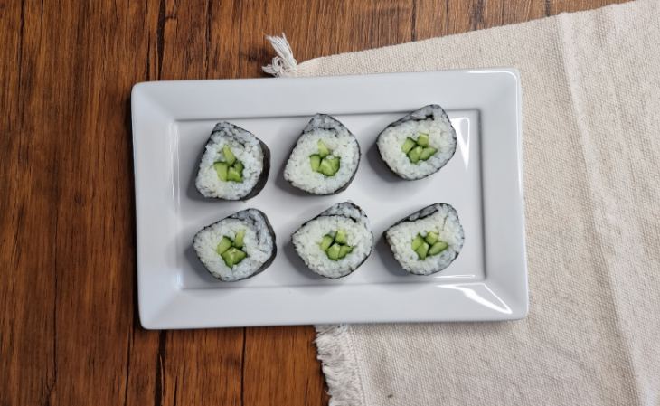 Um recipiente contendo hossomaki de pepino.