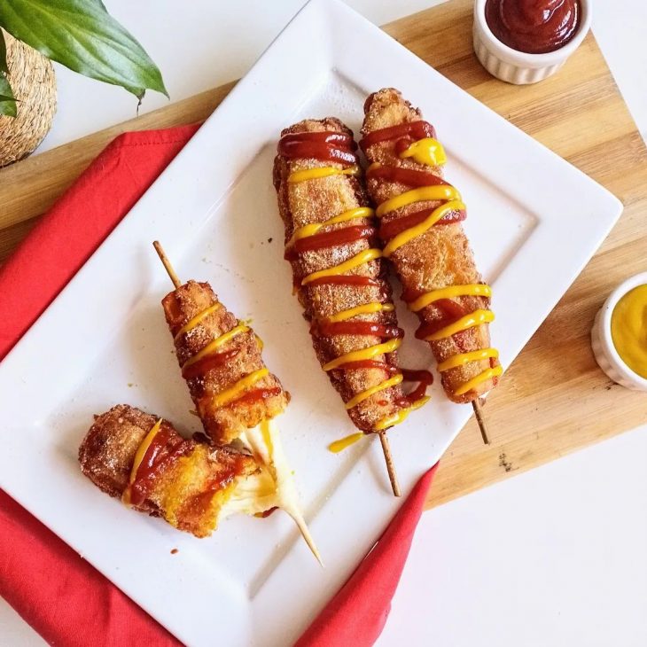 Corn dog é uma salsicha no palito com queijo mussarela, revestida com massa  de farinha e frita. comida de rua coreana de cachorro-quente