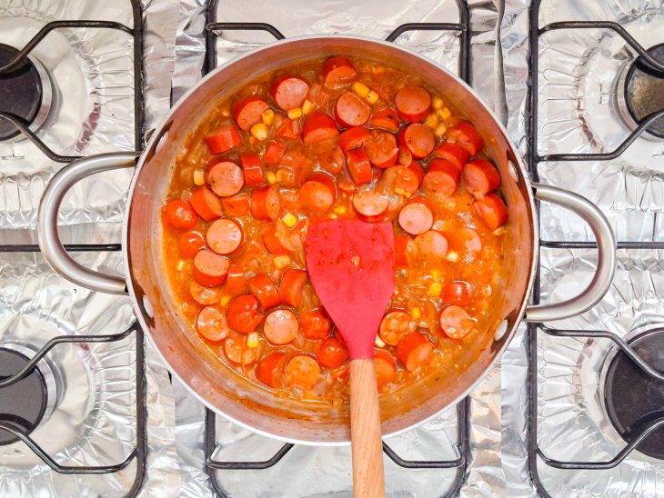 Molho de tomate e o milho adicionados na panela.