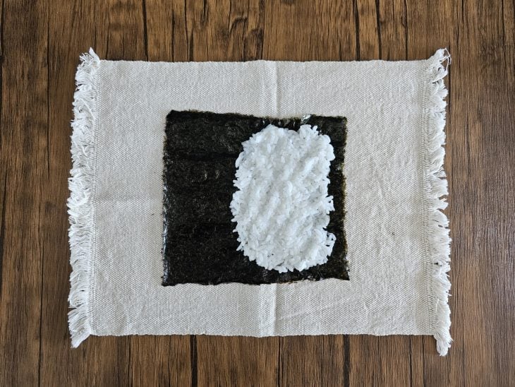 Um pano com folha de nori com uma porção de arroz.