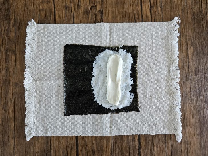 Um pano com folha de nori com uma porção de arroz e cream cheese.