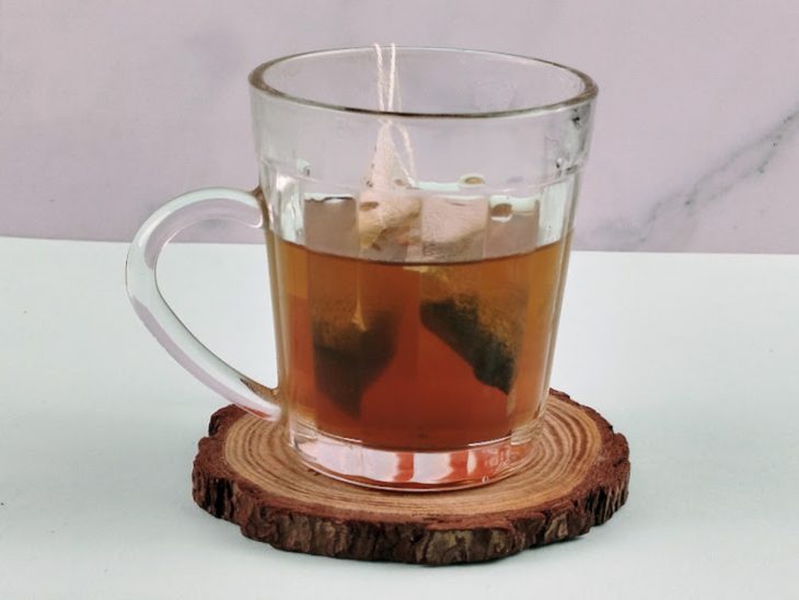 Sachês de chás infusionando em uma xícara de vidro com água.