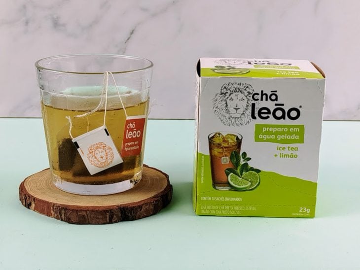Sachê de chá em infusão em uma xícara com água gelada.