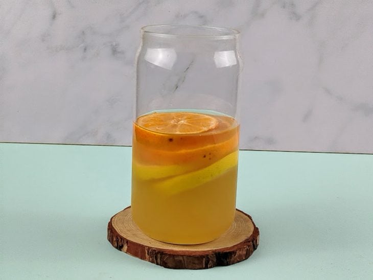 Suco de limão-tahiti, rodelas dos outros limões e gelo dentro de um copo de vidro.