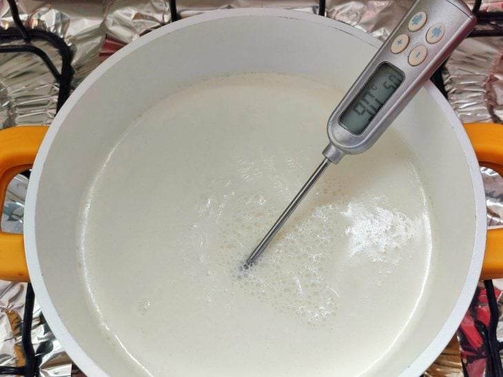 Panela com o leite e o termômetro culinário medindo a temperatura dele.