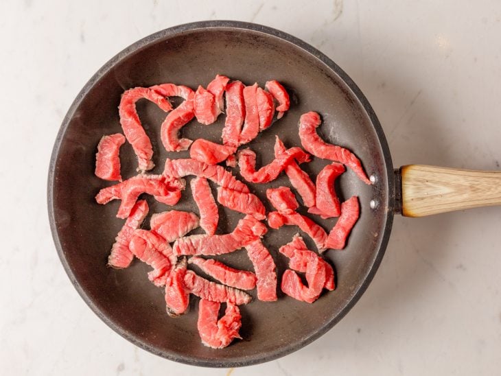 Frigideira com tirinhas de carne fritando.