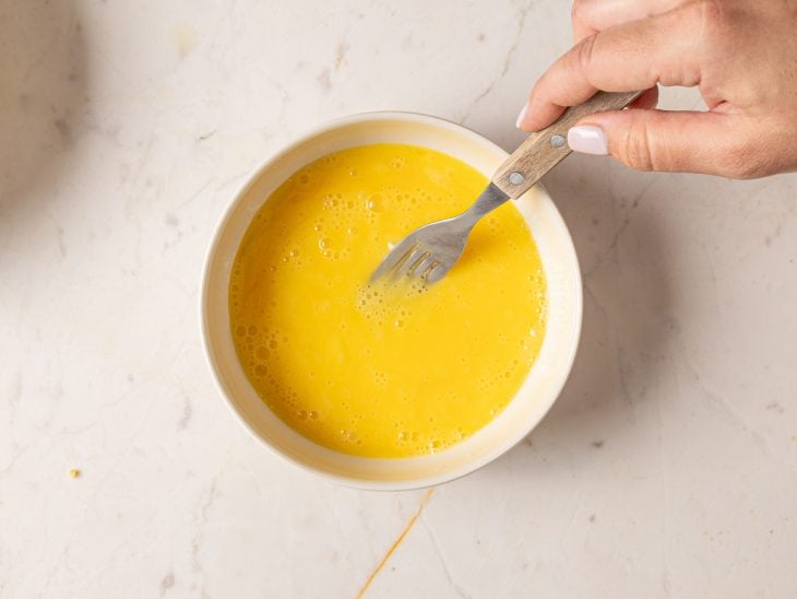 Um recipiente com ovo batido com garfo.