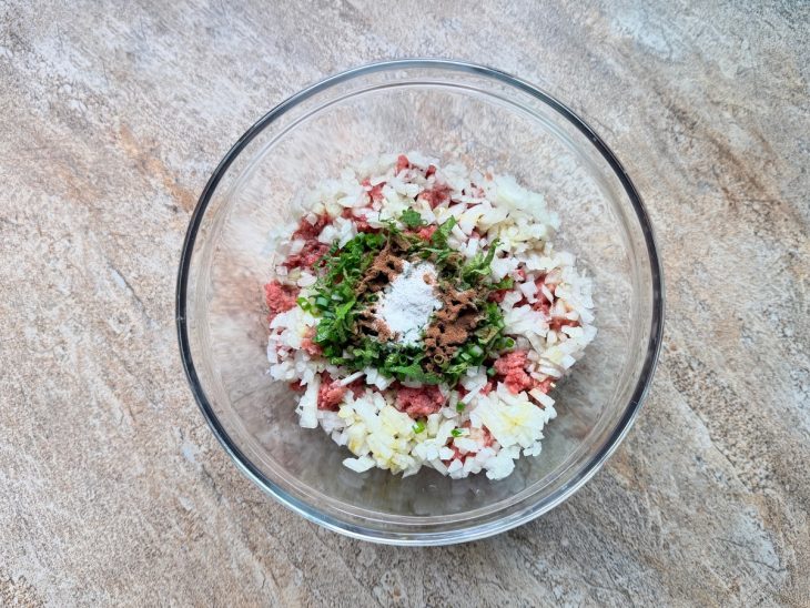 Numa tigela, a carne moída, junto da pimenta, cebola e cheiro-verde.