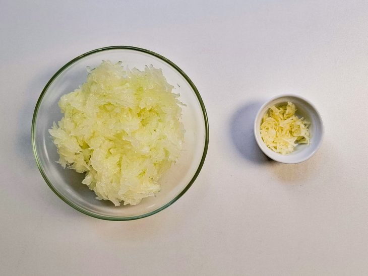 Alho e cebola picados e reservados em recipientes distintos.