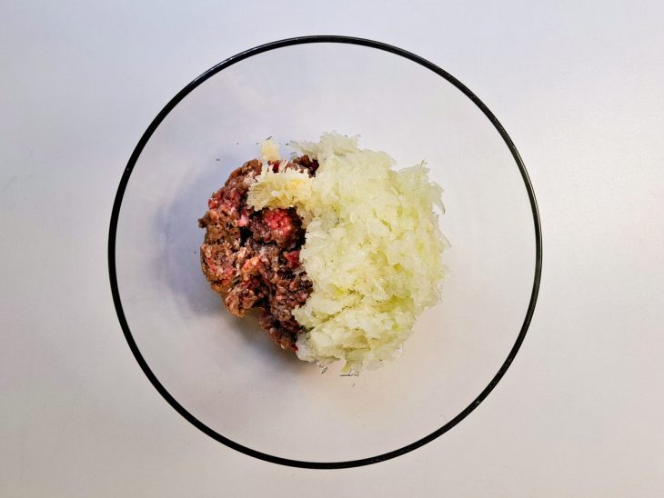 Alho e cebola colocados na tigela com a carne.