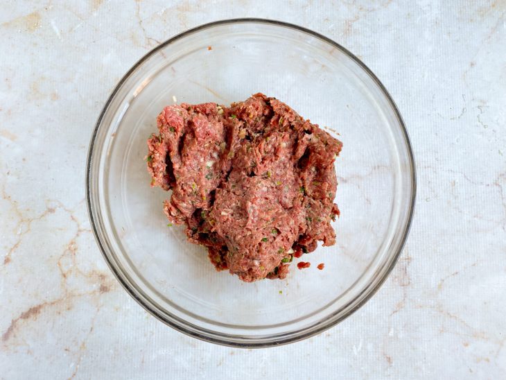 Carne moída com o creme de cebola, o alho amassado, os temperos secos e as ervas picadas.