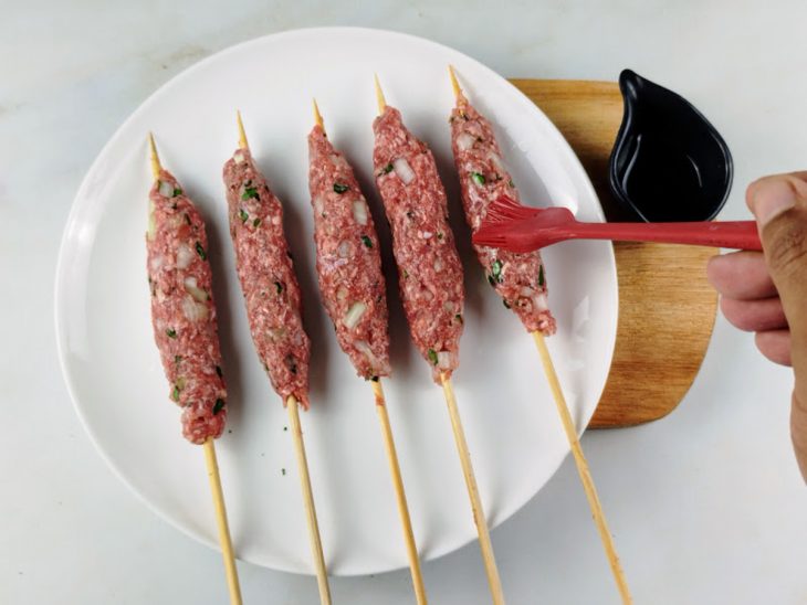 Azeite pincelado sobre a carne nos espetos.