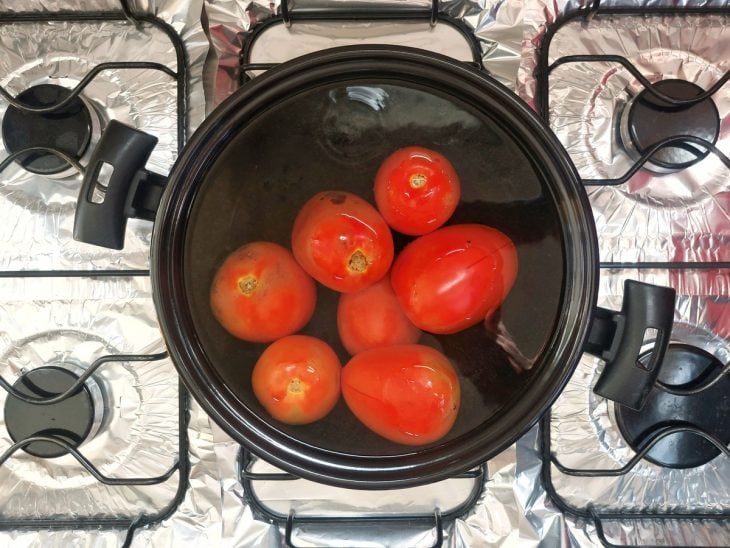Uma panela contendo água fervente e tomates.