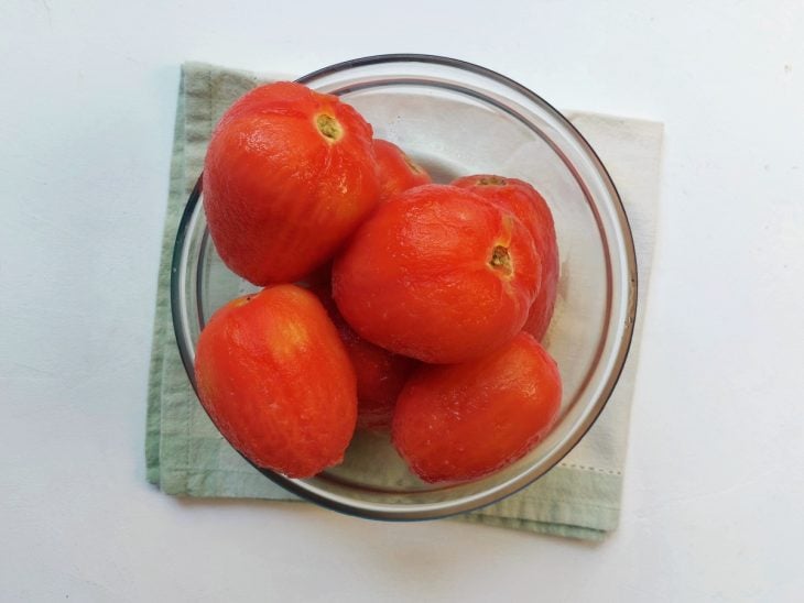 Um recipiente contendo tomates sem cascas.