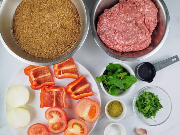 Ingredientes para a receita de kibe cru reunidos em uma bancada.