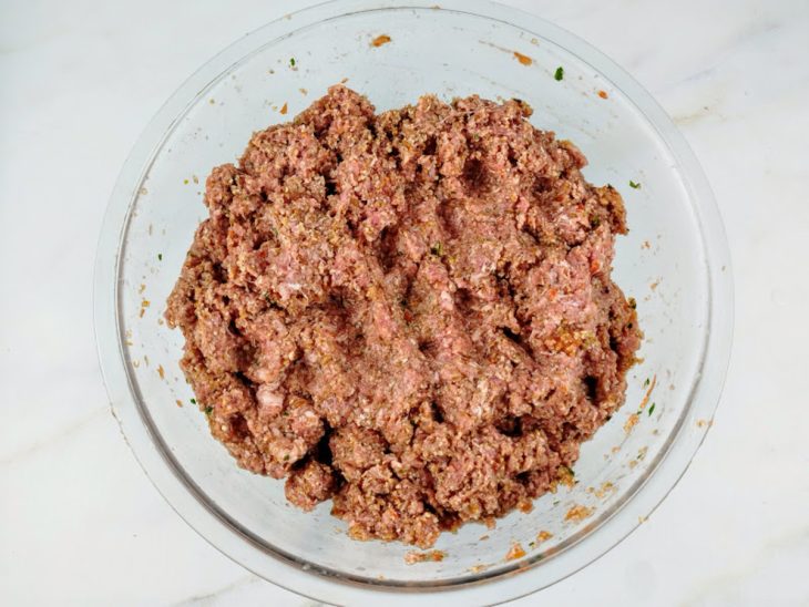 Trigo hidratado, carne moída e mistura do liquidificador em uma tigela de vidro.