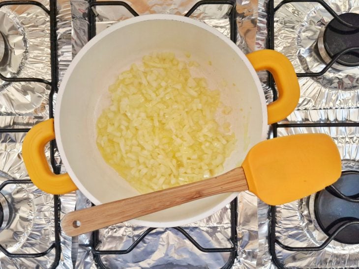 Uma panela com azeite, cebola e alho ao fogo.