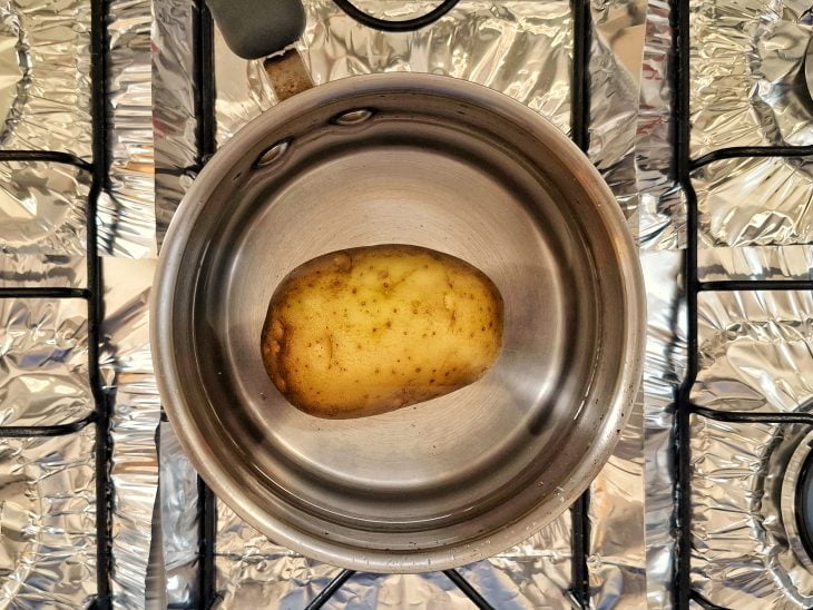 Uma panela com água e batata ao fogo.