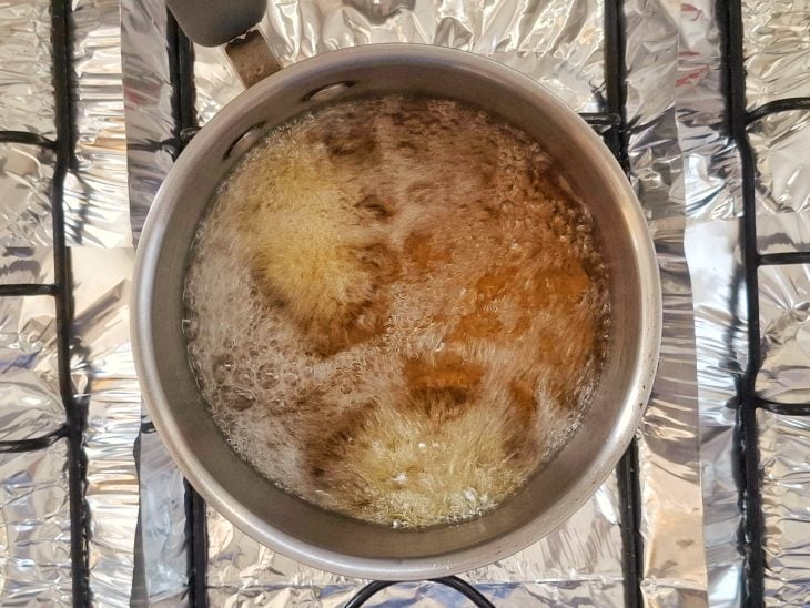 Uma panela com óleo quente e kibes fritando.