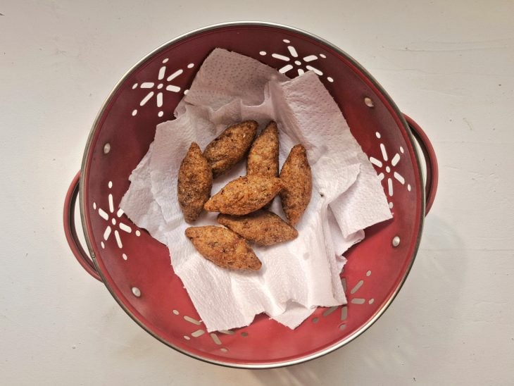 Um recipiente forrado com papel-toalha e kibes fritos.