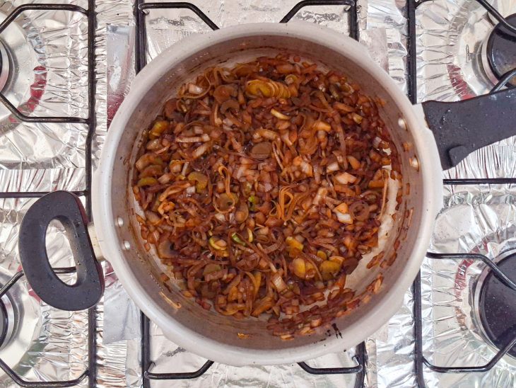 Cebola, alho-poró e salsão refogados na panela.