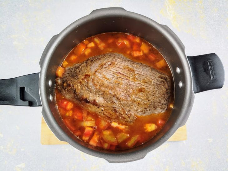Carne e água adicionadas na panela de pressão.