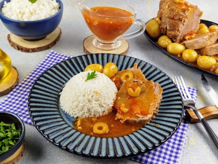 Lagarto com molho italiano servido com uma porção de arroz em um prato individual.