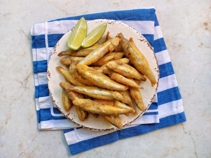 Lambaris fritos prontos, servidos em prato com limão.