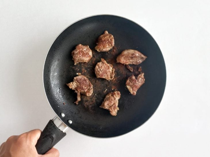 Acém em pedaços refogado em uma frigideira.