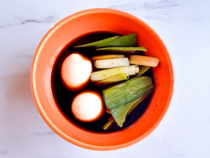 Num pote, o talo que sobrou do alho-poró, shoyu e ovos mergulhados no shoyu.