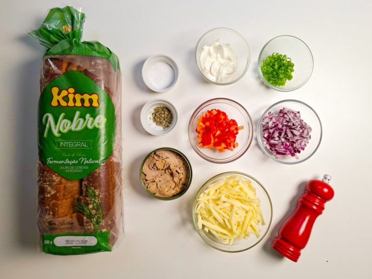 Ingredientes organizados sobre a bancada com cebola e tomate sendo picados.