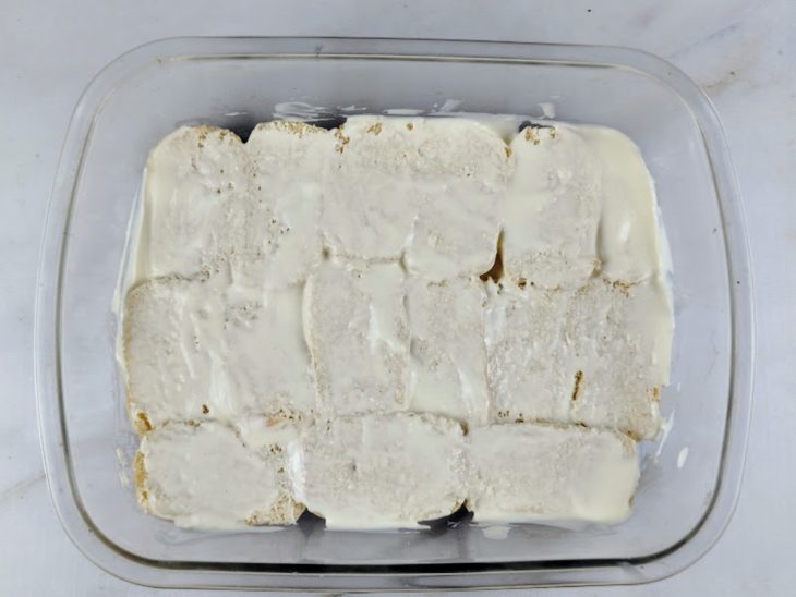 Requeijão espalhado sobre as bisnagas na travessa.