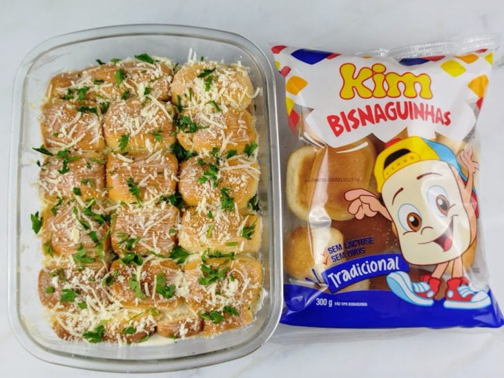 Parmesão e salsinha salpicados sobre as bisnagas na travessa.