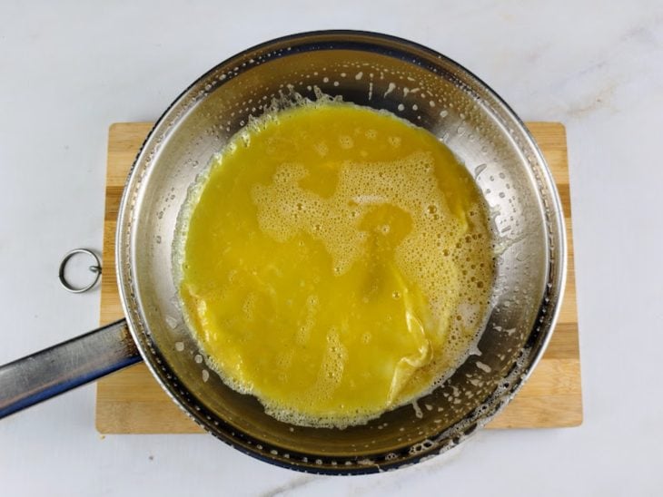 Uma frigideira com manteiga e os ovos.