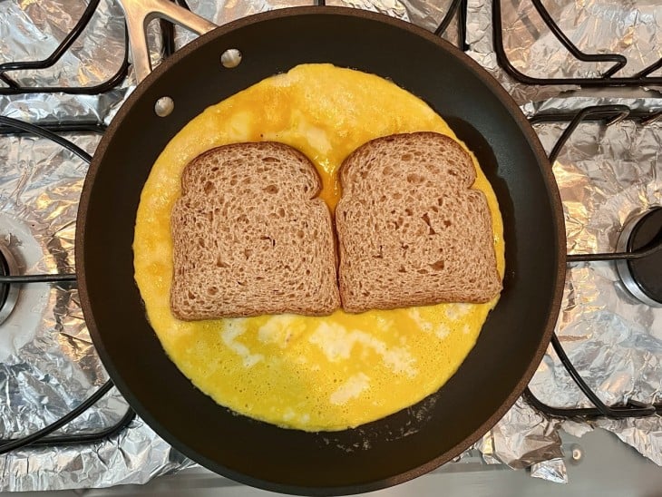 Uma frigideira com omelete e duas fatias de pão.