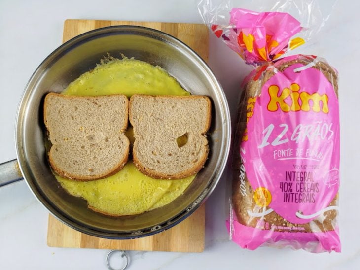 Fatias de pão dispostas na frigideira sobre os ovos.