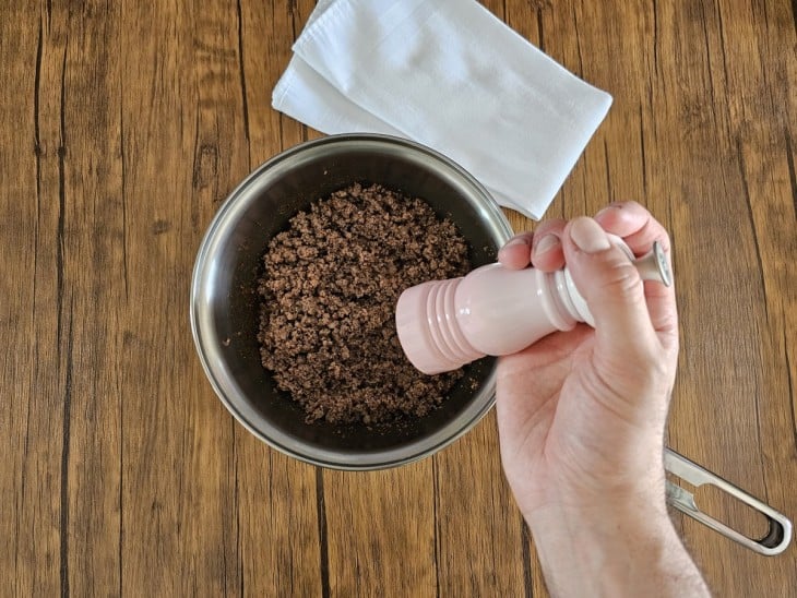 Uma panela contendo carne moída refogada sendo temperada.