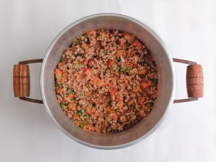 Molho de tomate, açúcar e cheiro-verde adicionados a panela.