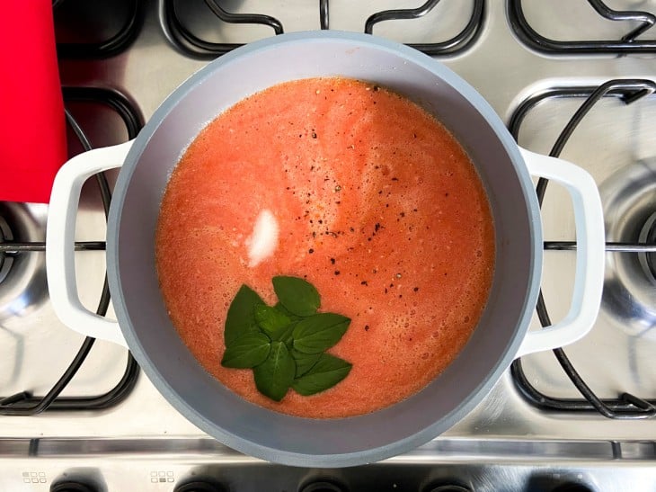 Uma panela com molho de tomate e manjericão.