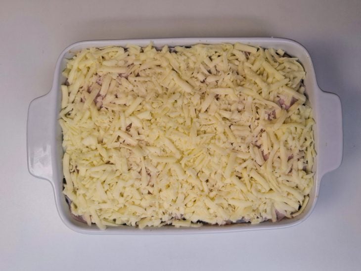 Camadas de presunto, queijo, carne moída e berinjela adicionados a travessa.