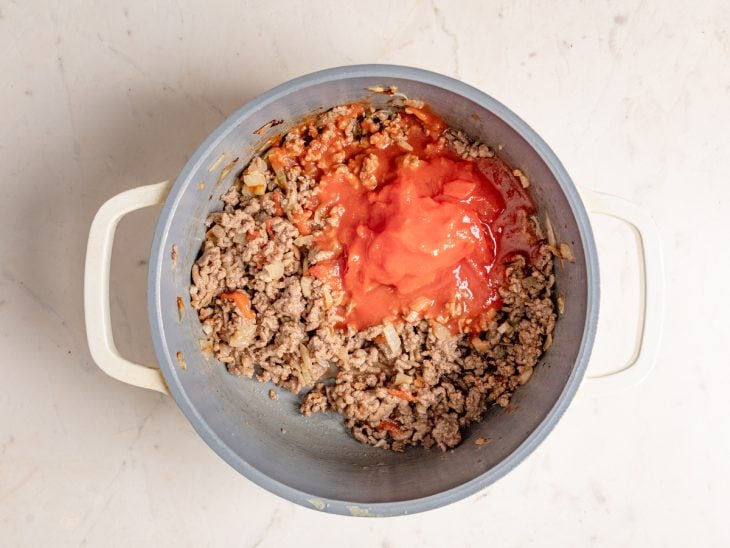 Carne temperada com molho de tomate em uma panela.