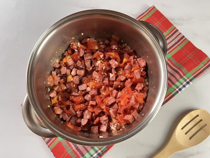 Uma panela refogando calabresa picada e tomate.