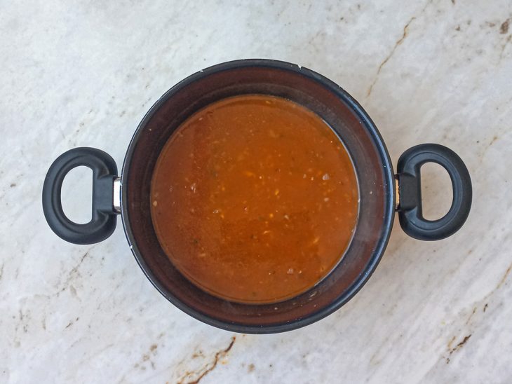 Molho de tomate, sal e água quente adicionados a panela.