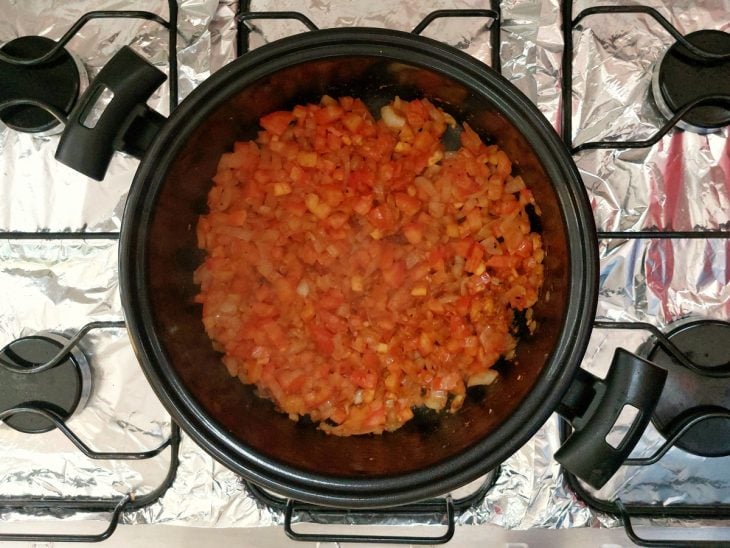 Uma panela refogando a cebola, alho e tomate.