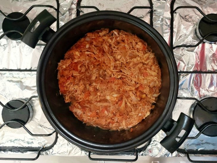 Uma panela refogando a cebola, alho, tomate e frango.